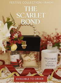 A festive gift set styled for Rakhi, featuring a black gift box with a pearl handle, a bottle of Agarwood Charpai, a decorative pouch, and a white ceramic mug that reads 'BROTHERS are just born to disturb SISTERS'. The image has text overlays reading 'FESTIVE COLLECTION • RAKHI', 'THE SCARLET BOND', and 'AVAILABLE TO ORDER'.